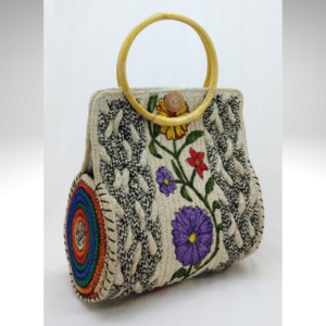 Handcrafted natural jute handbag featuring a round yellow bamboo handle, intricate white rope floral embroidery, and a hand-painted multicolor rainbow rope accent on the side.