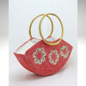 Handcrafted mini jute handbag in a soft coral pink tone, featuring a round yellow bamboo-style handle and intricate white rope floral embroidery on the front.