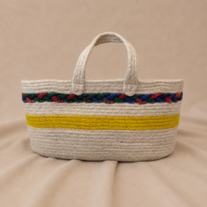 Handcrafted natural jute basket tote bag with double jute handles, open oval interior, yellow stripe detail, and colorful woven accent bands around the top edge.