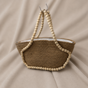 Handcrafted natural jute handbag with rounded woven body, wooden bead handle, zipper closure, white fabric-lined interior, and earthy textured fiber finish.